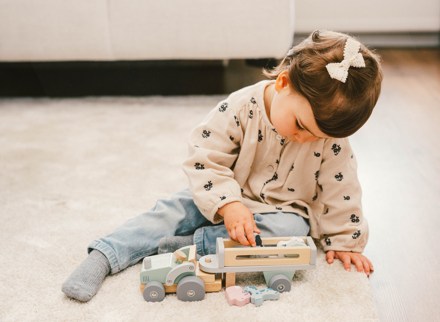 Child playing with animal truck wooden toys on a carpeted floor