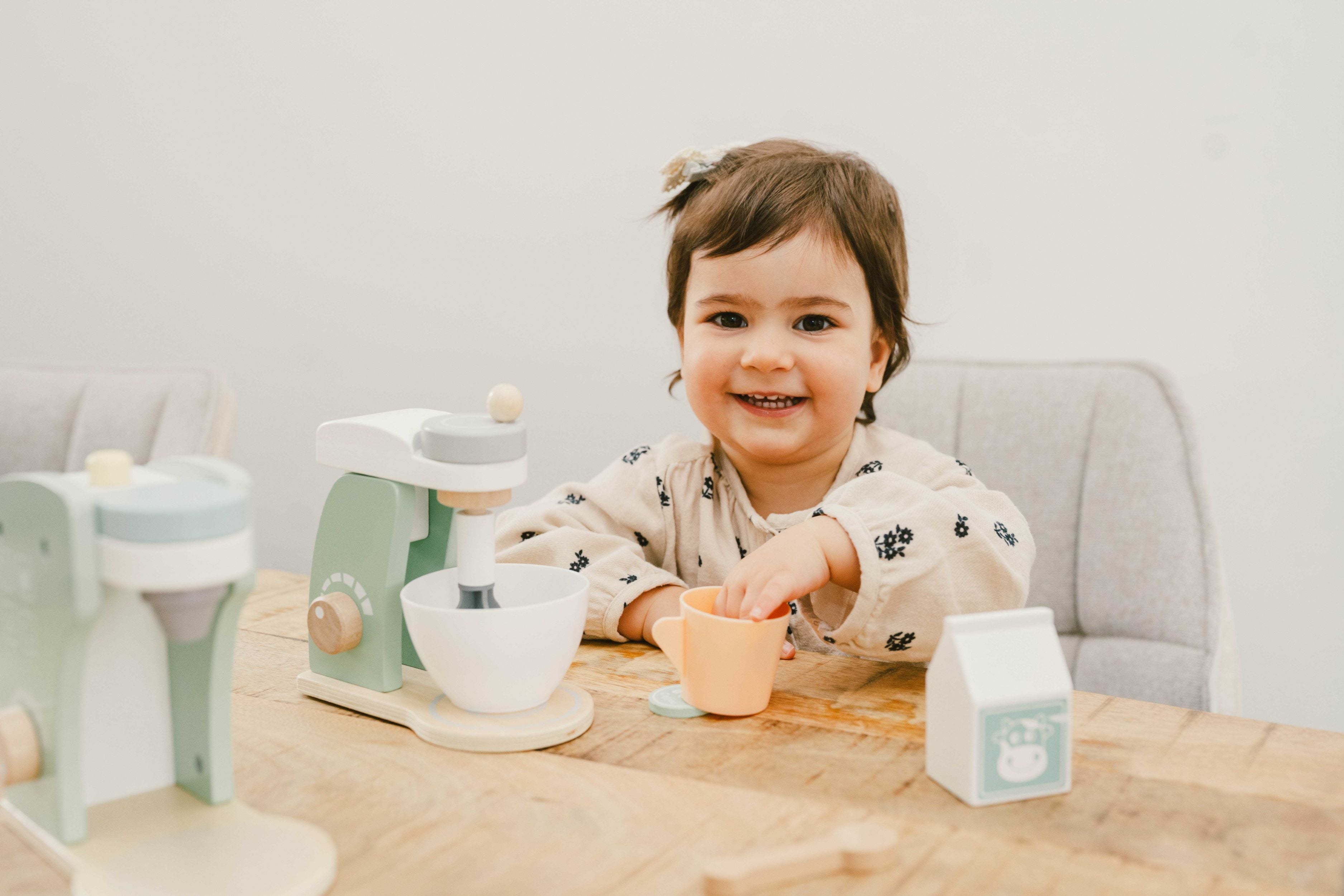 Little girl playing with the Wooden Wonders eco-friendly wooden kitchen set, coffee machine and kitchen mixer