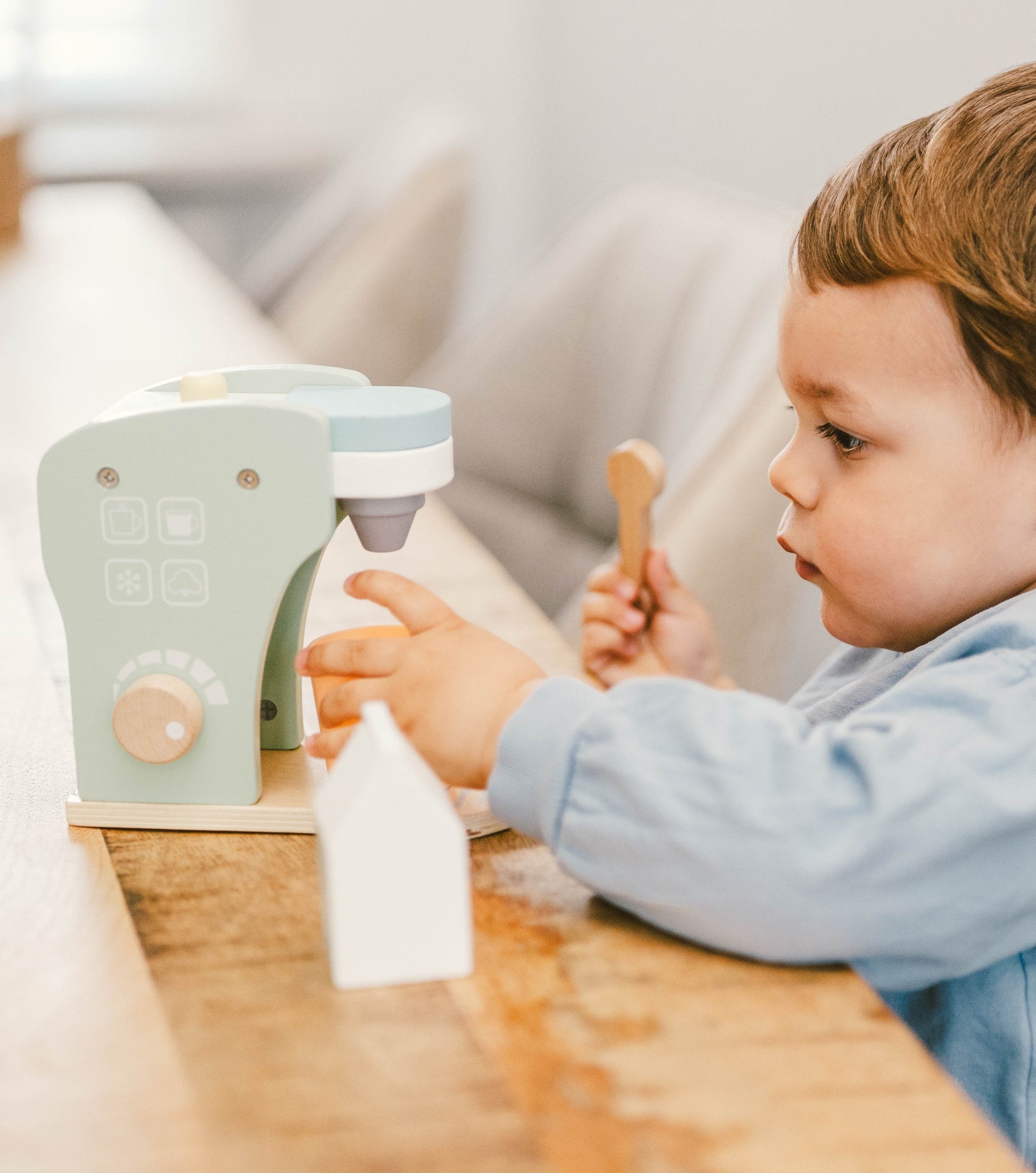 Child playing with a toy kitchen set on a wooden table