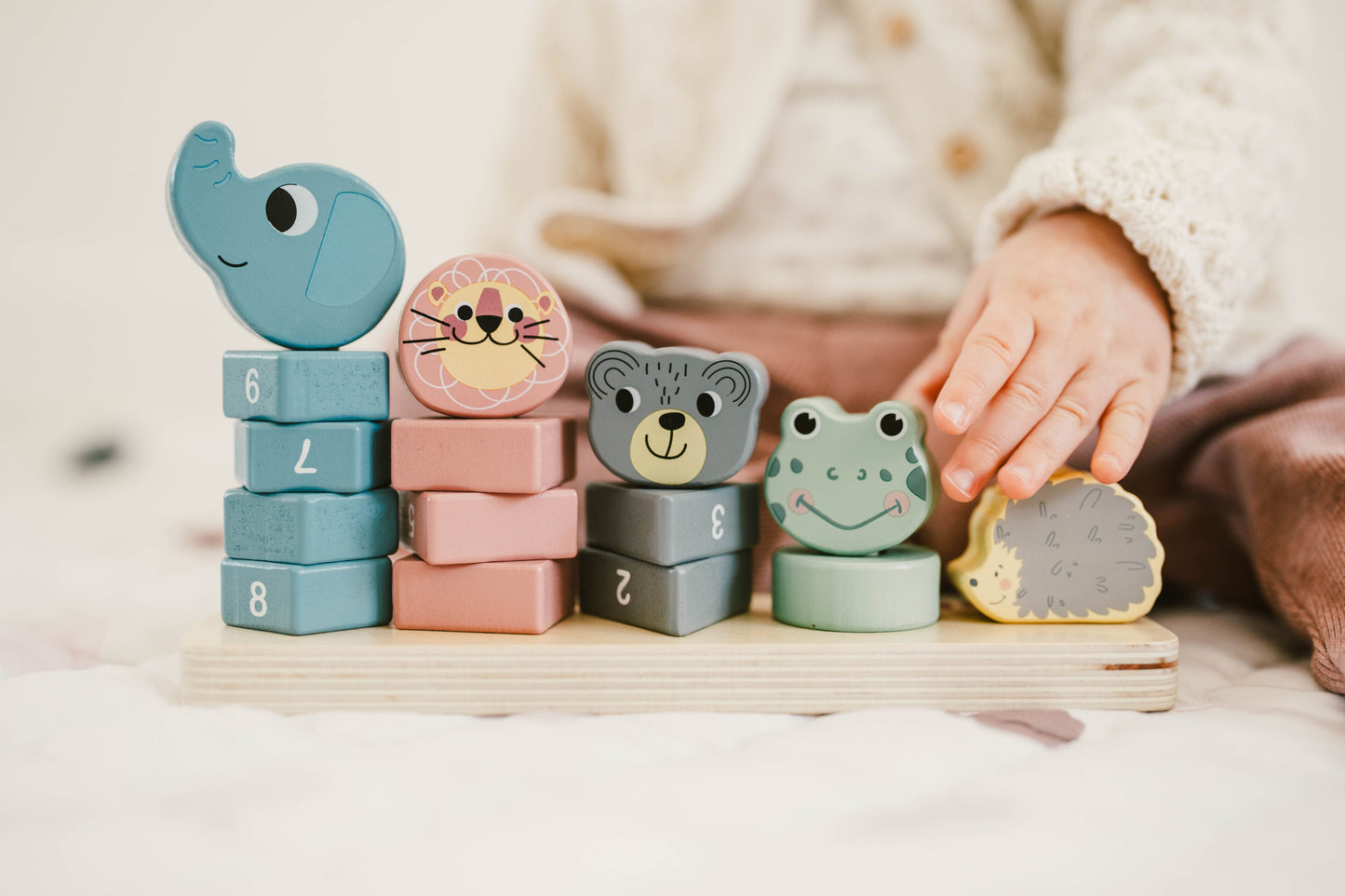 girl´s hands playing with a stacking tower with animal blocks
