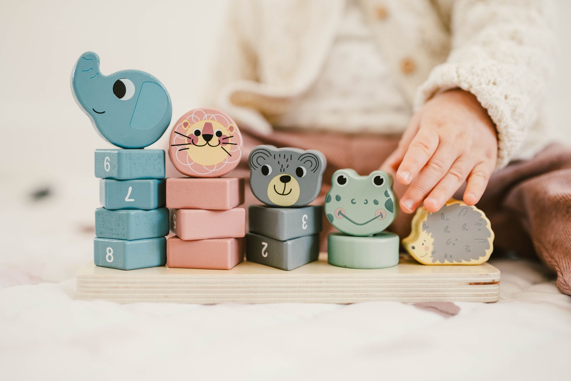 girl´s hands playing with a stacking tower with animal blocks