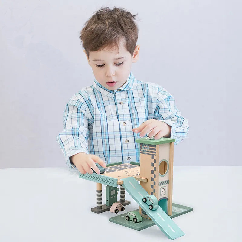 Boy playing with a wooden playset featuring a parking garage with elevators and a ramp, gas station with vehicles, and a repair shop.