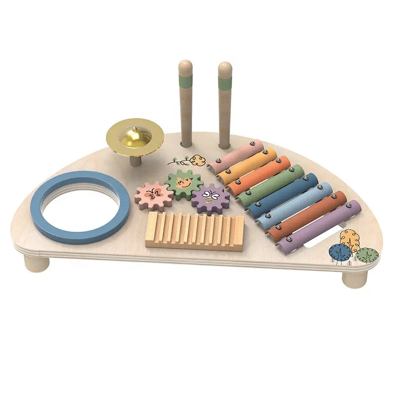 A wooden music center toy with multiple colorful instruments and interactive elements, including a xylophone, cymbal, guiro, and spinning gears, along with drumsticks. The toy is crafted from natural wood with pastel colors and nature-themed illustrations.