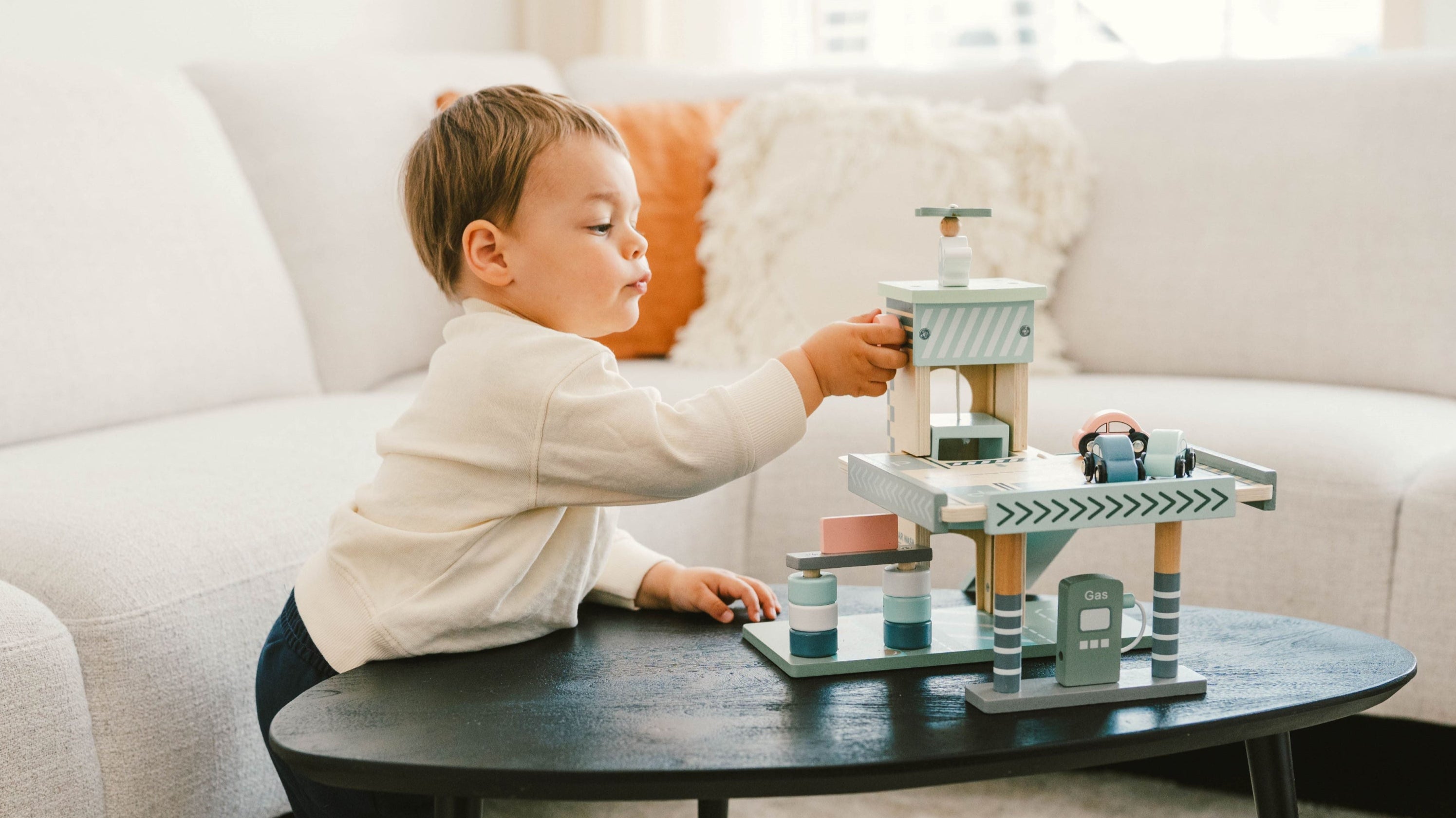Little boy playing with the Wooden Wonders eco-friendly wooden parking garage toy